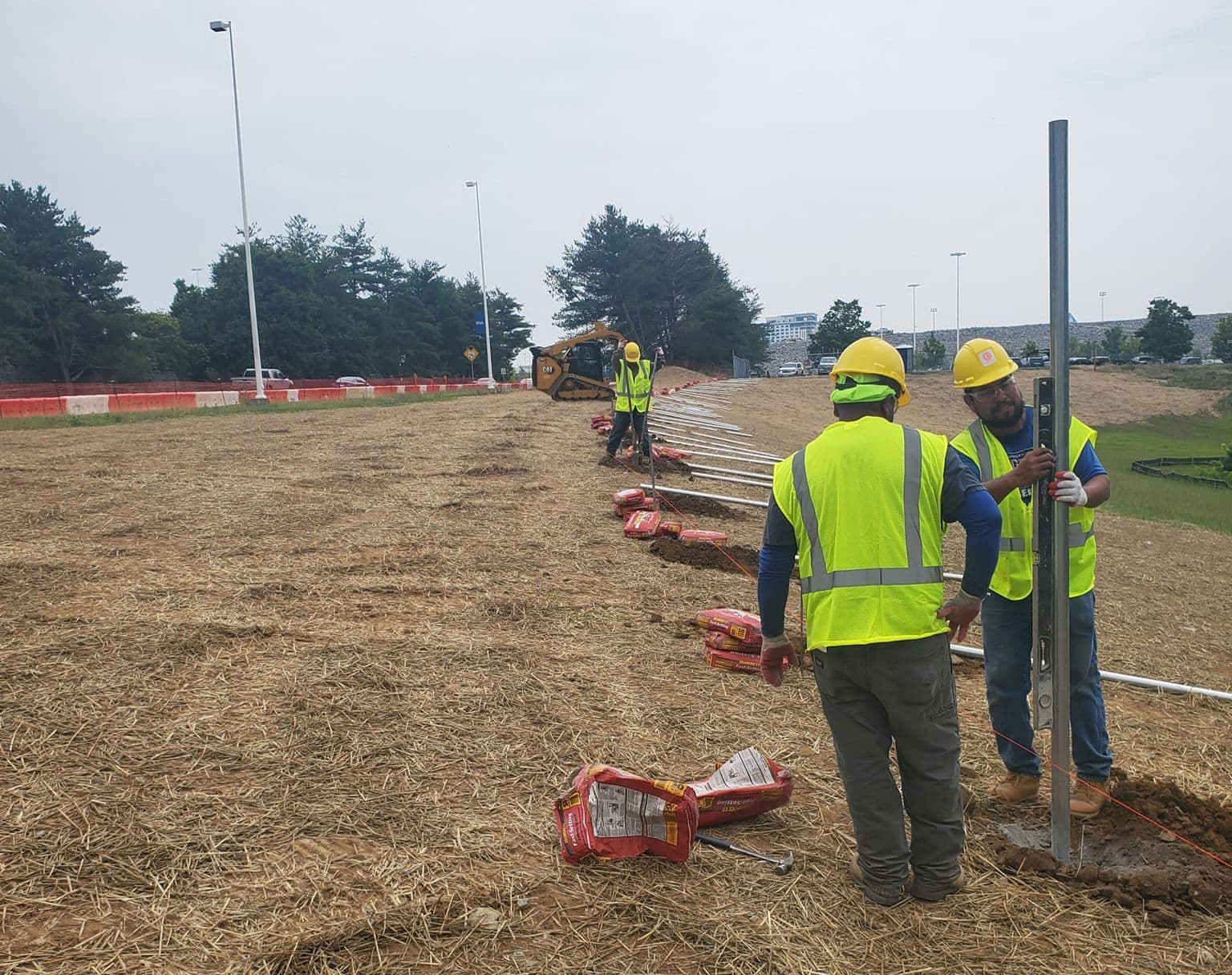 A Sands Fence crew setting steel posts for a commercial perimeter fence on a graded site