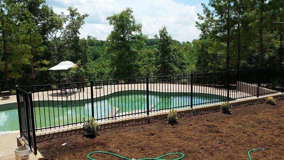 Photo of wroght iron black fence around a private inground pool that is on a steep slope hillside