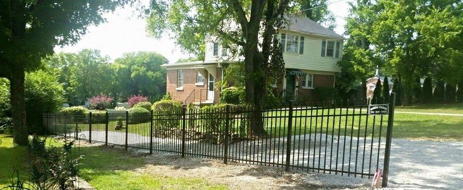 Photo of driveway with wood fence on either side. The fence is a wood fence with two horizontal slats and an upper "x style" slat.