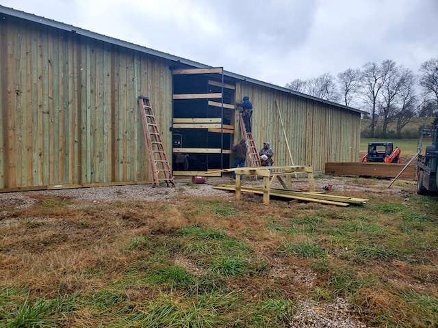 Photo of metal gate with metal electric fence framed with wood posts and rails