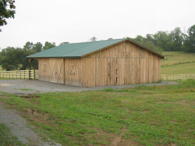 Photo of enclosed wood barn. Sliding doors form the entry. The vertical boards are a striking change from the traditional horizontal board barn construction. Wood framed squares spaced along the front and sides of the barn with wooden "X" desgins in the squares give the appearance of windows. A large star of David above the sliding doors is outlined in wood at the hayloft height. Wood lattice trim deliniates the support header over the sliding doors. The barn is energized with a large security light over the barn doors and the rear of the barn sports a stone chimney.