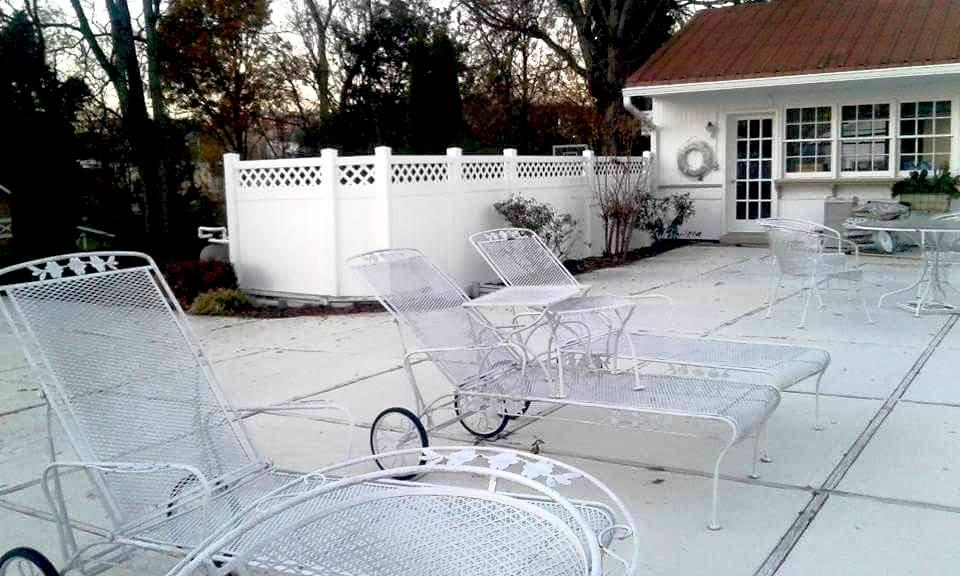 Photo of vinyl privacy fence in white sheltering a pool patio from the pool pump and other pool supplies