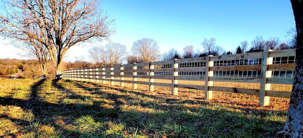 Photo of wood horizontal rail fence with wire mesh between the horizontal slats