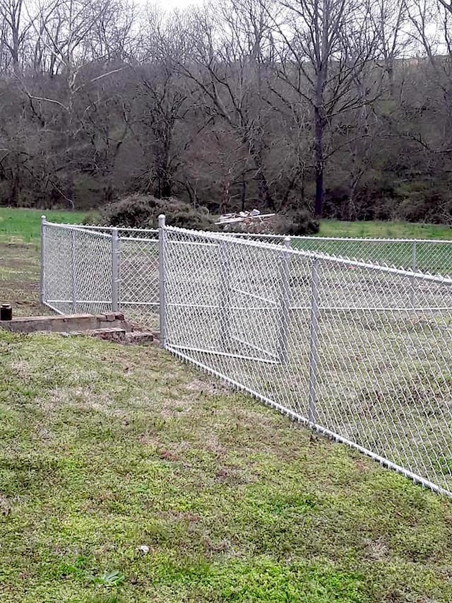 Photo of a property with a chain link traditional silver fence with a wood privacy fence framing the back yard. of the home