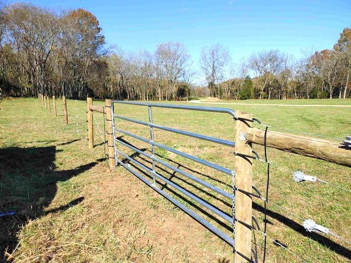 Photo of metal gate with metal electric fence framed with wood posts and rails