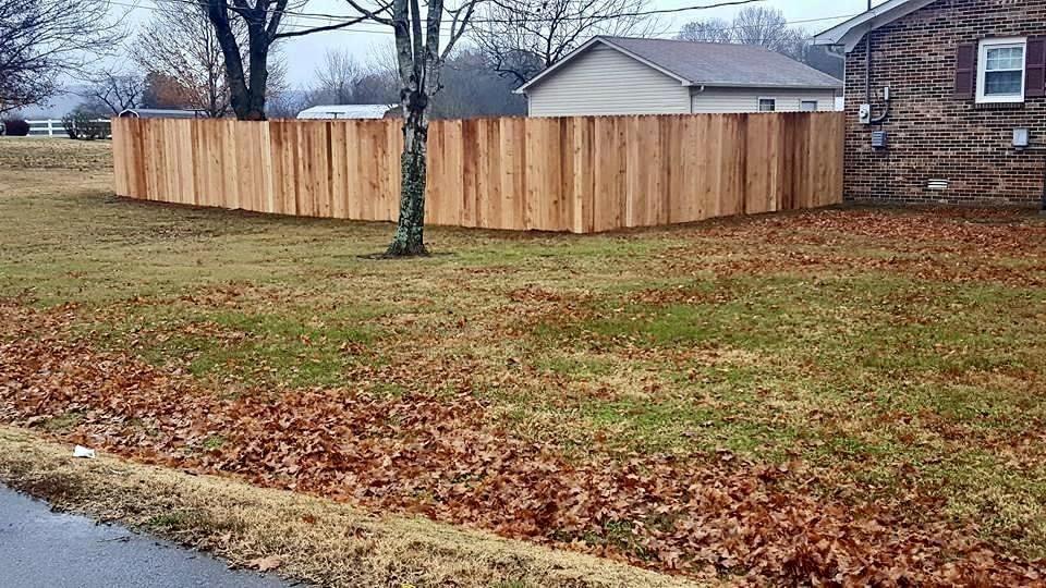 Photo of driveway with wood fence on either side. The fence is a wood fence with two horizontal slats and an upper "x style" slat.