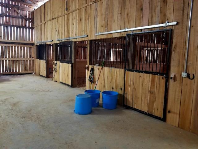Photo of interior of horse barn showing stalls and gated upper parts of the horse stalls